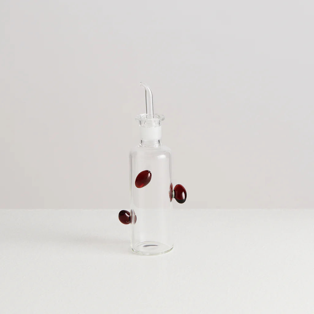 A glass bottle with glass olives made for pouring balsamic vinegar