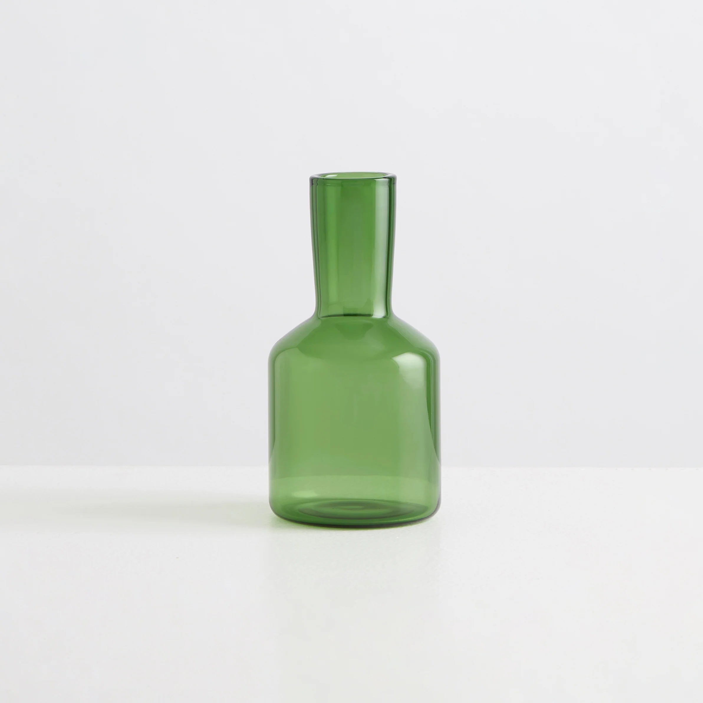 A clear green carafe on a white background