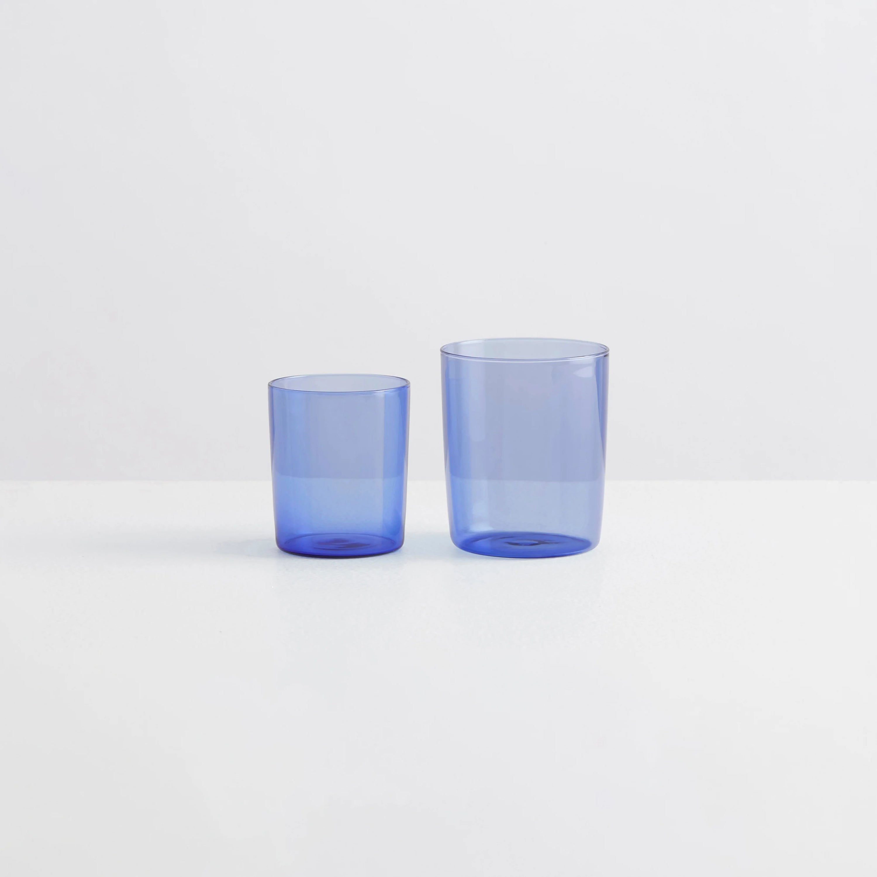 Two clear blue drinking glasses, one small and one large on a white background