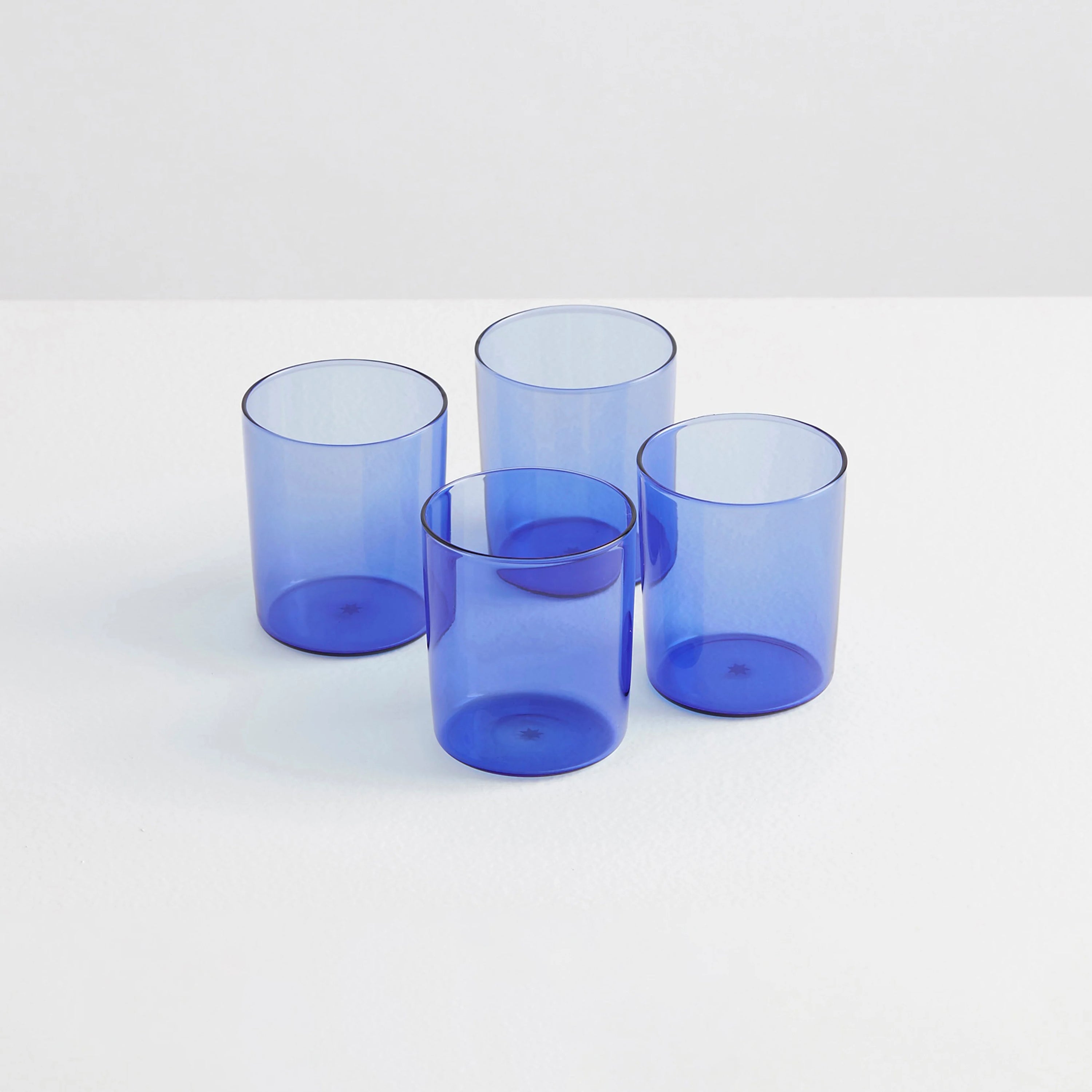 Four clear blue drinking glasses on a white background