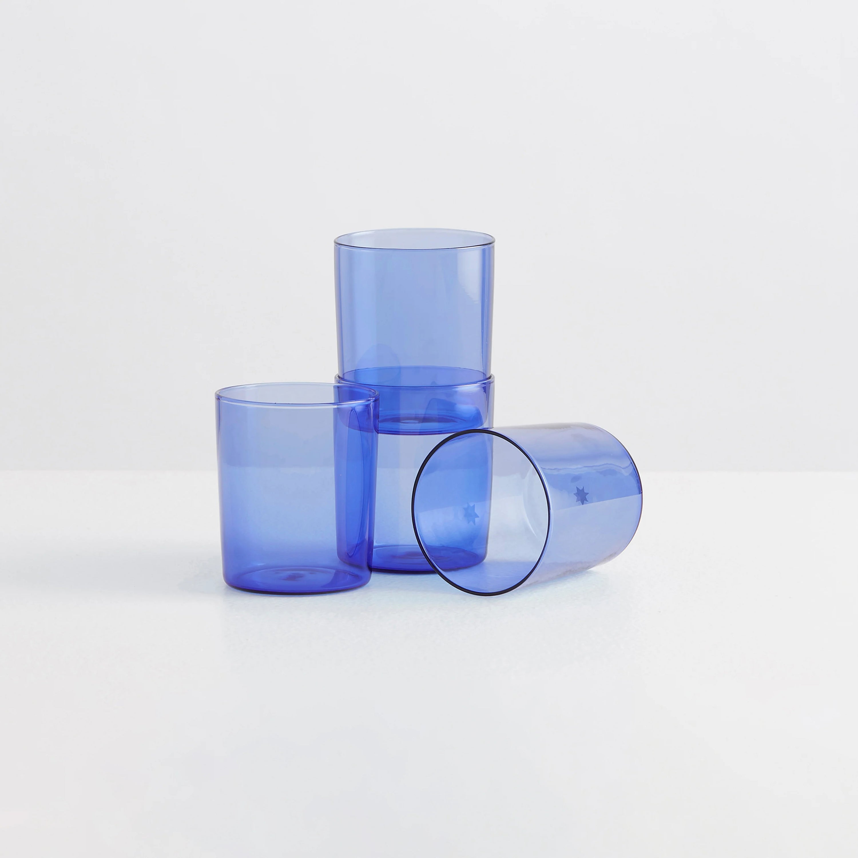 Four clear blue drinking glasses on a white background