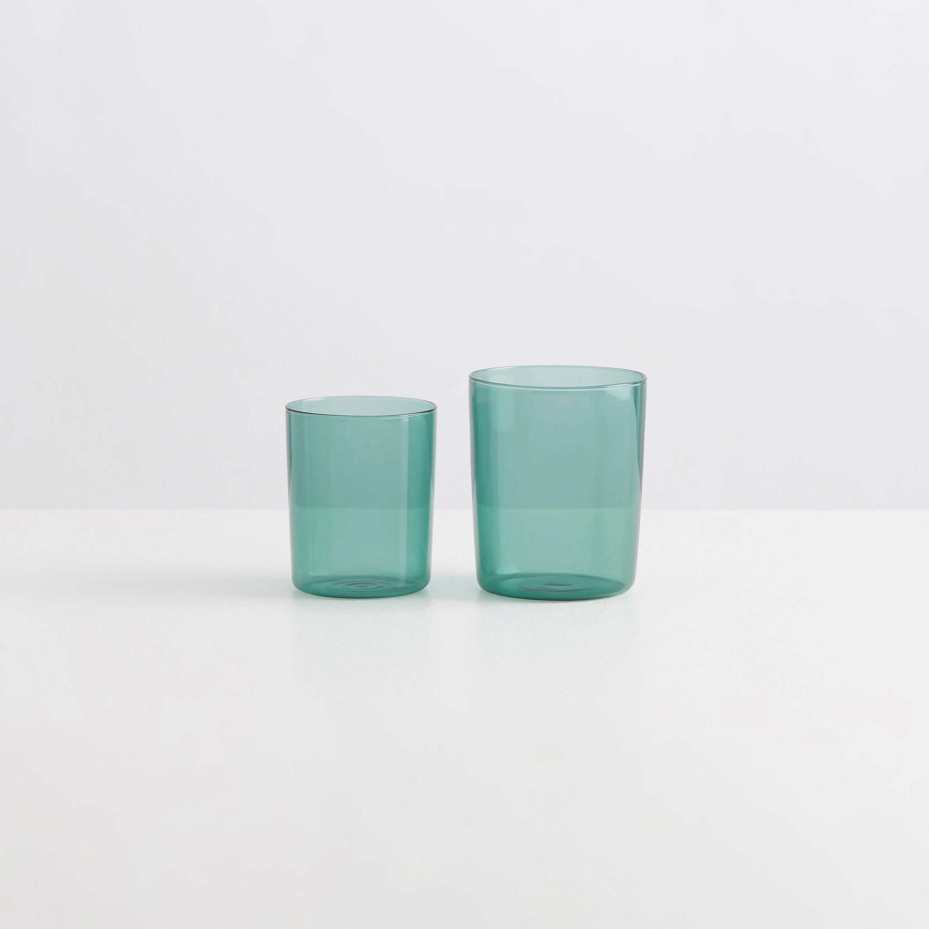 Two teal coloured clear drinking glasses on small and one large
