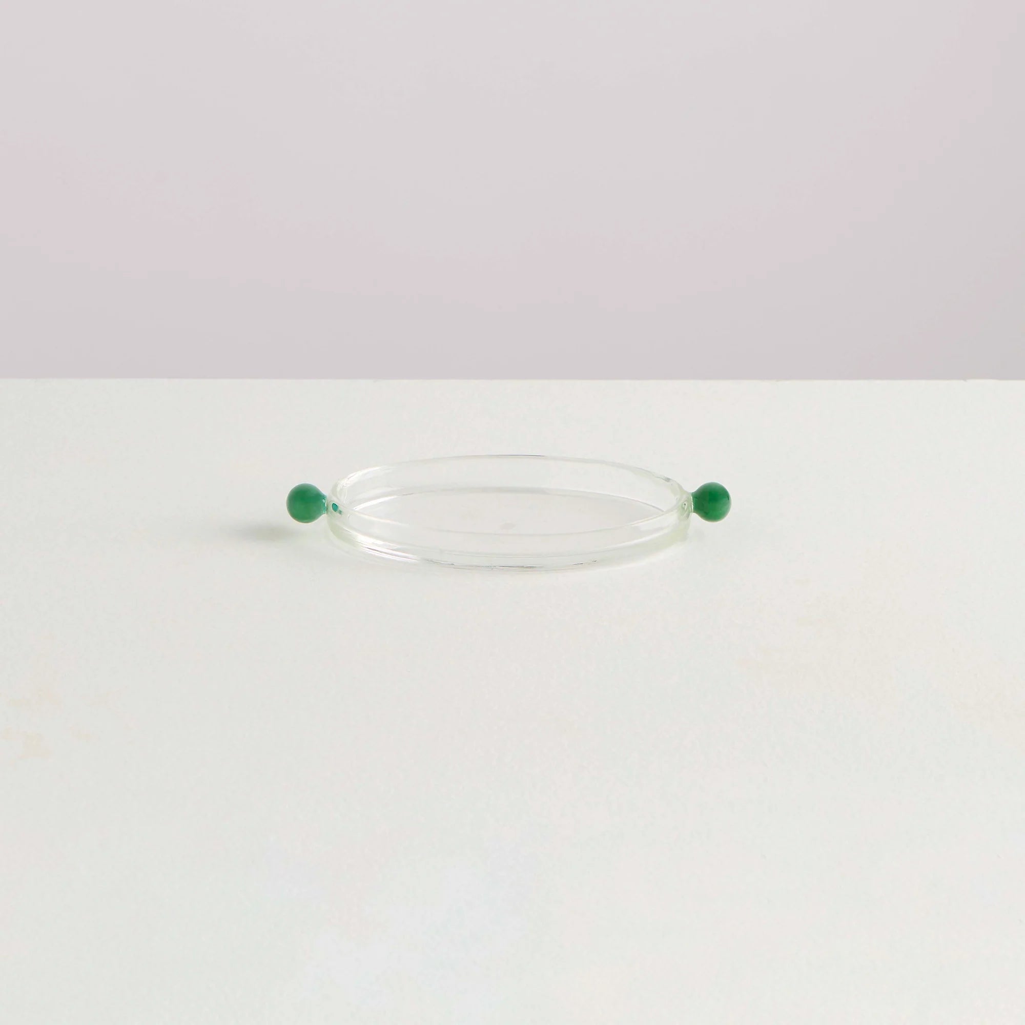 A clear glass platter with round green glass olives on either side