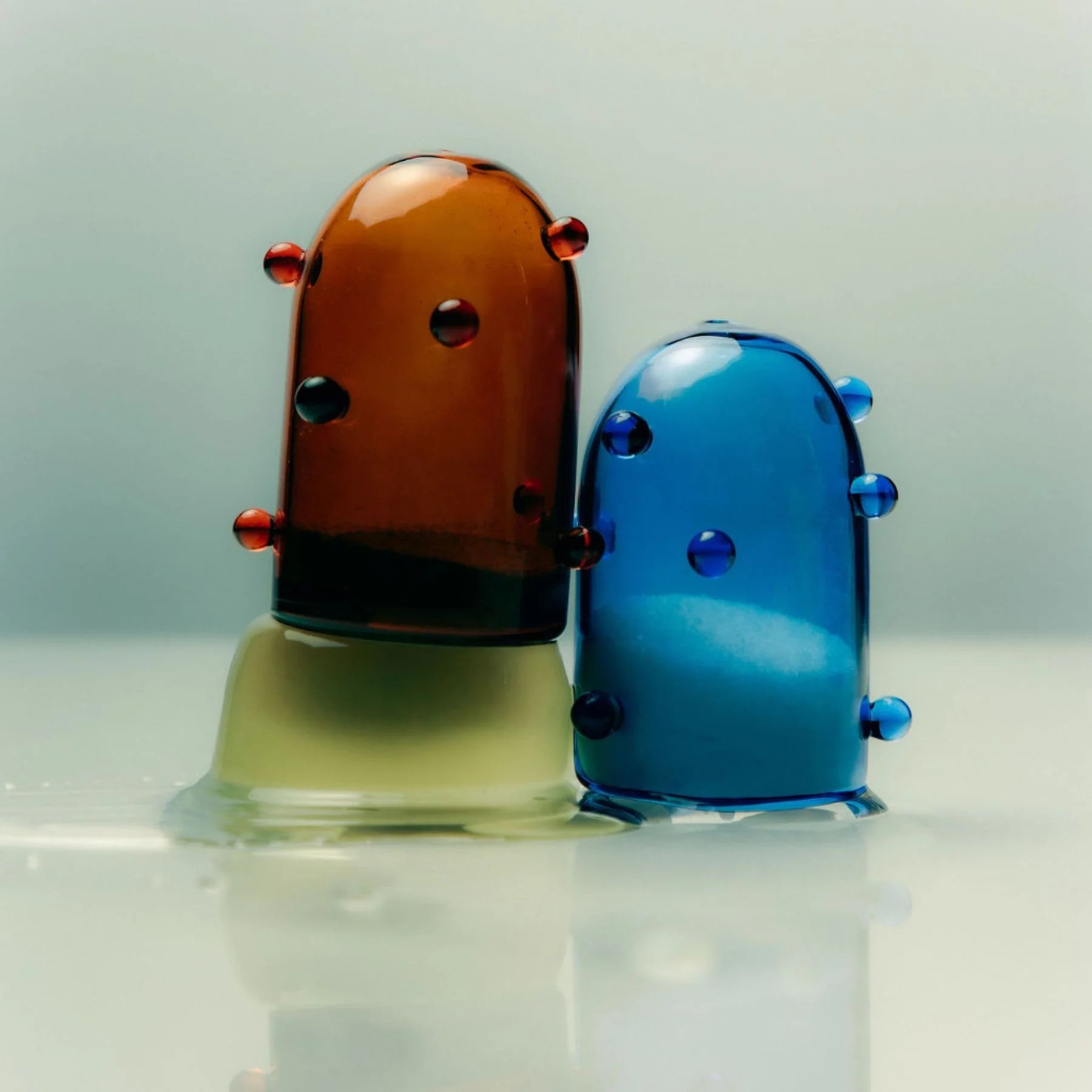 Two clear glass salt and pepper shakers one blue and one amber coloured