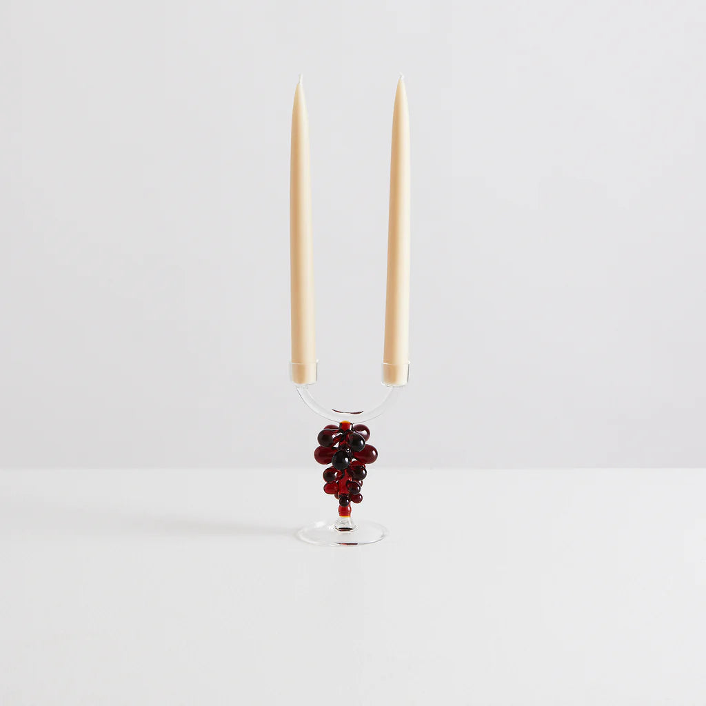 A glass candelabra with red grape details