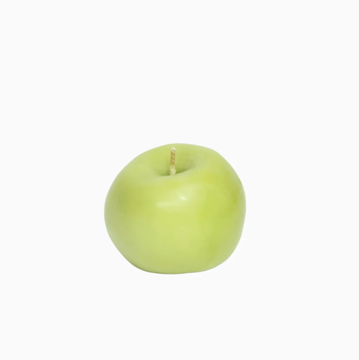 green apple shaped candle on a white background