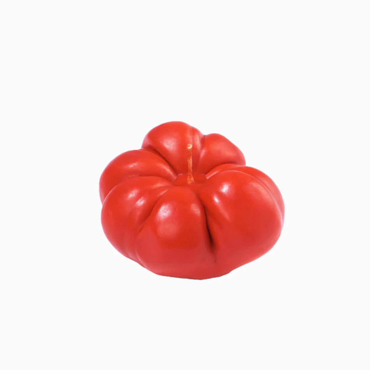 An heirloom tomato shaped candle on a white background