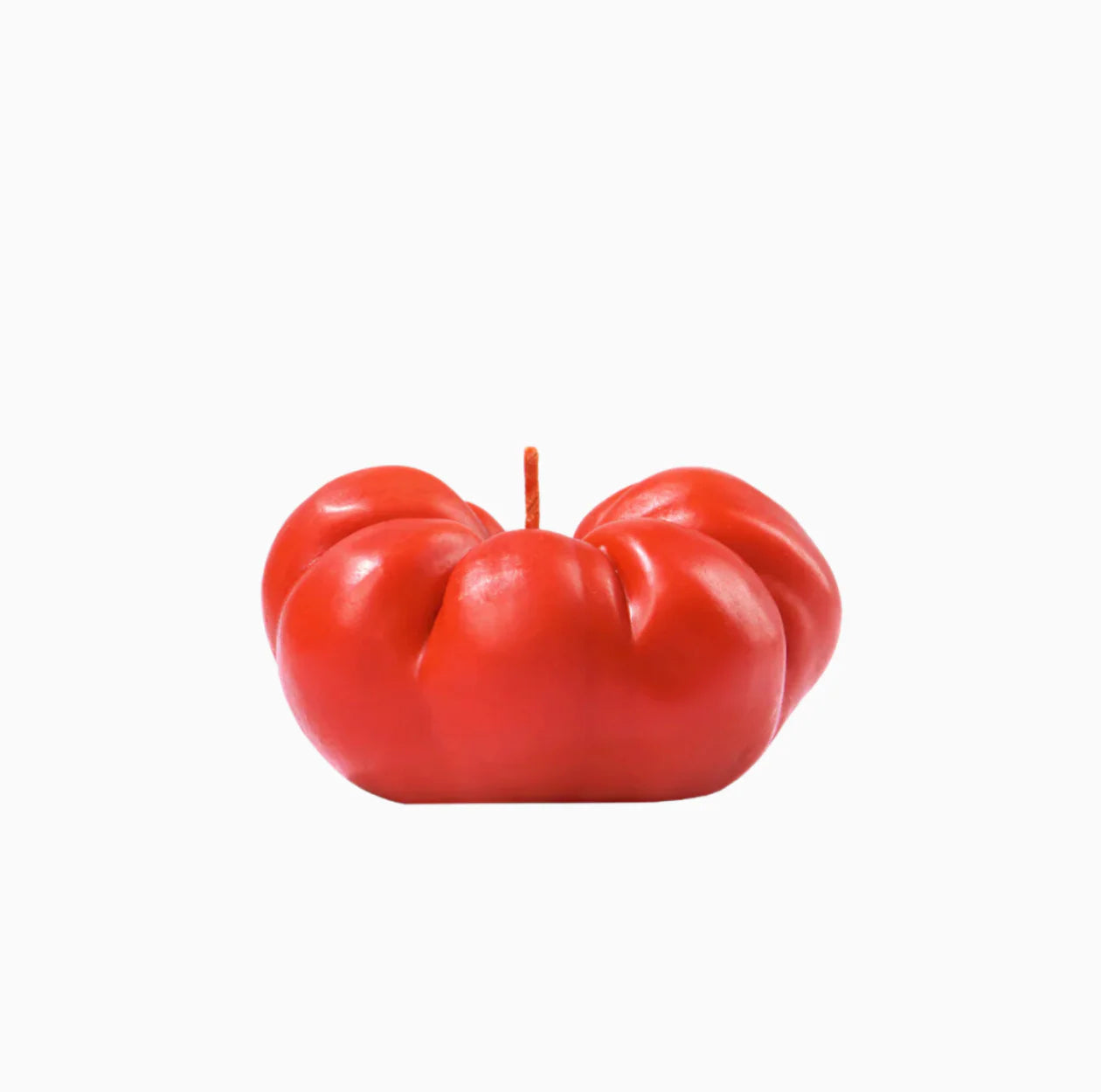 An heirloom tomato shaped candle on a white background